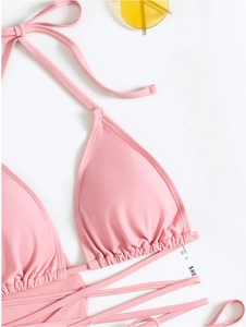 Detailansicht eines rosa Halter-Bikini-Tops mit Rüschenkanten und Etikett S