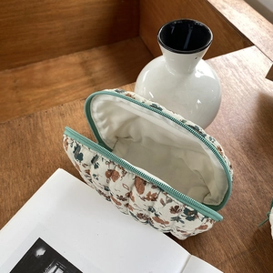 Gewatteerde make-up tas met bloemenprint in bruin en groen op houten bureau