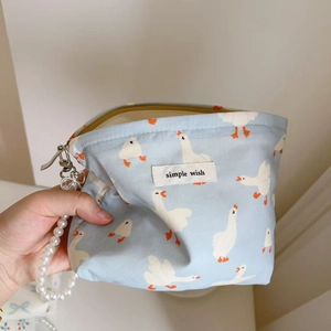 Close-up of small blue fabric pouch with white duck print and pearl beaded handle