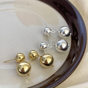 Dettaglio macro di orecchini a sfera in oro e argento lucido su vassoio in ceramica