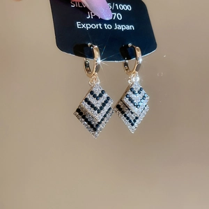Détail de boucle d'oreille losange élégante sertie de diamants avec tige en argent S925