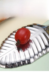 Macro detail of leaf-shaped golden stainless steel tray with mirror finish and texture