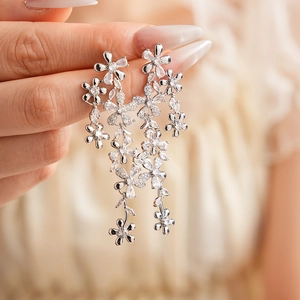 Close-up of sparkling zircon flower tassel earrings held to show fine jewelry details