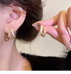 Detail of golden double-ring earrings with white mother-of-pearl and pavé zircon stones
