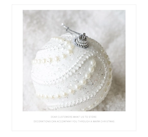 Vue rapprochée d'une boule de Noël blanche de 8cm avec paillettes argentées et perles