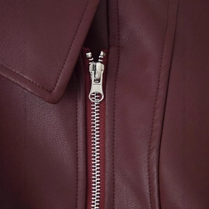 Détail de veste en similicuir bordeaux avec fermeture éclair en métal argenté et coutures