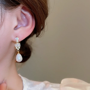 Macro view of 18k gold plated drop earrings with white pearls and sparkling zircons