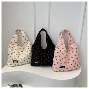 Detailed close-up of corduroy tote bags with strawberry pattern in white, black and pink