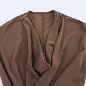Detailed close-up of brown pleated neckline fabric showing rich texture and draping