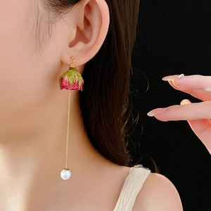 Boucles d'oreilles rose éternelle avec chaîne dorée et perle sur fond noir profond