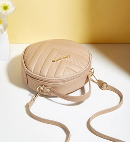 Detailed top view of a round quilted crossbody bag with wave embroidery and gold zipper