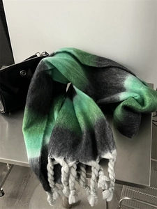 Close-up of fluffy green and black gradient scarf featuring thick decorative tassels