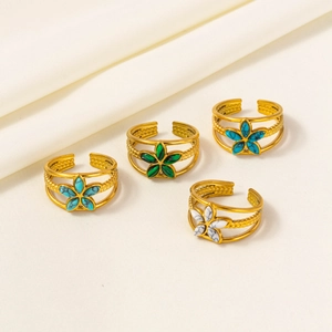Detail of four gold adjustable floral rings with colored stone petals on fabric