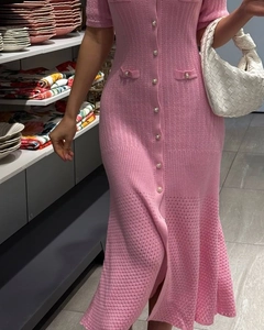 Detailed view of pink knitted dress featuring pearl buttons and delicate ribbed texture