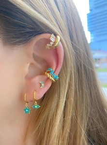 Macro detail of gold-plated star and moon earrings with turquoise stones on model