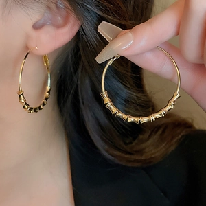 Detail of large gold bamboo textured hoop earrings showing intricate segment patterns