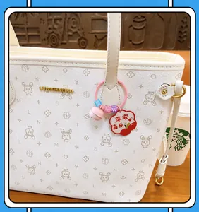 Nahaufnahme eines Schlüsselanhängers mit rosa Glocke und Apfel-Anhänger an Tasche