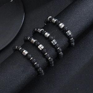 Detail of black lava stone beaded bracelets with custom engraved silver metal cylinders