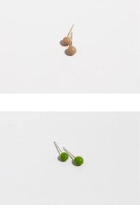 Detail view of minimalist ball stud earrings in cream and green enamel finish