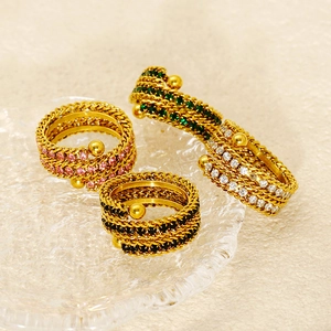 Detail of multi-layer 18k gold plated braided rings with pink green white and black crystals