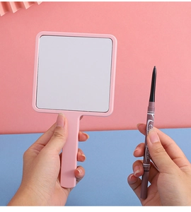 Close-up of pink square handheld beauty mirror with a clear view and makeup pencil
