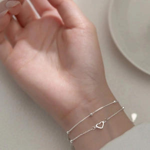 Minimalist double layer silver heart bracelet featuring delicate beads and hollow heart charm