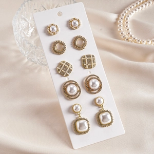 Five-pair gold earring set with faux pearls and rhinestones on a white display card