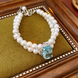 Gros plan d'un bracelet double rangée de perles avec détails argent et gemme bleue