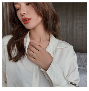Detailed view of a gold bamboo-textured ring with zircons worn on a model finger