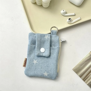Macro detail of light blue denim fabric texture and white star print on a compact card case