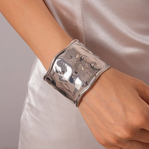 Détail d'un bracelet manchette large argenté avec une finition en métal martelé