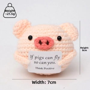 Pink crocheted pig doll holding a motivational card with size and weight specs