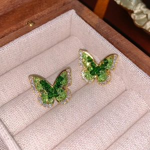 Macro shot of green zircon butterfly earrings with gold plating in a jewelry box