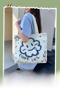 Detail of a large white canvas tote bag with a blue smiling cloud and cookie print