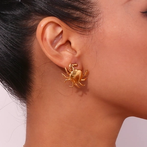 Detailed close-up of a model wearing a small gold-plated crab-shaped stainless steel stud earring