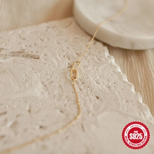 Close-up of S925 sterling silver golden double-ring link necklace on a stone base