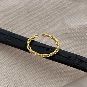 Macro view of golden braided chain knot ring on black leather strap with canvas texture