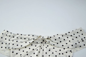 Detail of polka dot skirt with elegant knot design and layered ruffle textures