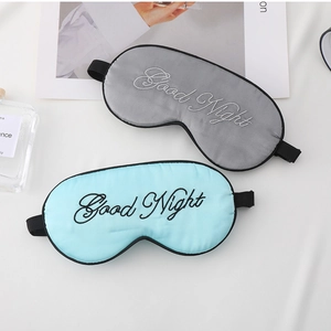 Detail of silk-like sleep masks in grey and light blue with Good Night embroidery