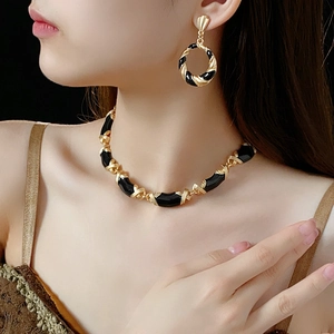 Close-up of model wearing vintage twisted black and gold enamel necklace and earrings set