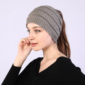 Detail view of a grey knitted ponytail headband featuring a chunky cable knit texture