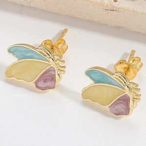 Macro shot of minimalist butterfly stud earrings with gold edges and blue purple wings