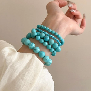 Detail showing five-piece turquoise beaded elastic bracelets with smooth round textures