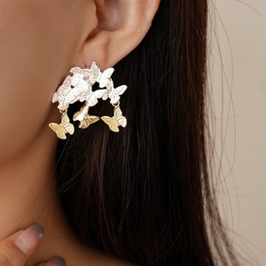 Gros plan sur des boucles d'oreilles papillon bicolores avec pompons en métal poli
