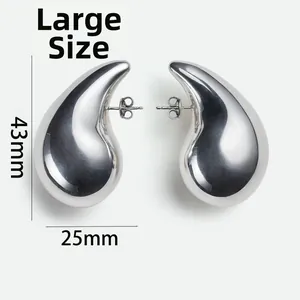 Macro detail of large 43mm polished brass teardrop earrings with a mirror finish