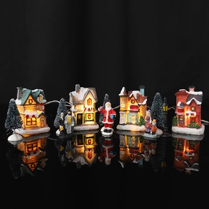 Detalle de una aldea navideña LED con casitas iluminadas, figuras y abetos en miniatura