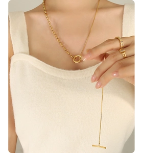 Detail of 18k gold plated OT buckle necklace and zircon ring on model with knit sweater