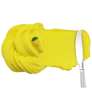 Close-up of yellow butter slime kit with pineapple charm and soft spiral texture