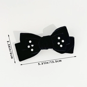Detail view of a black velvet bow hair clip with white pearls measuring 13.5cm x 6cm