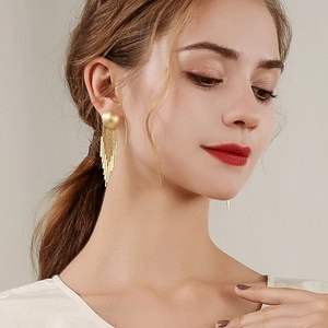 Elegant gold fringe drop earrings featuring minimalist metallic tassels worn by a model